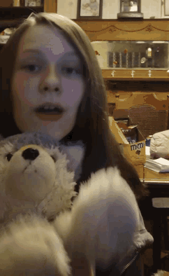 a girl is holding a teddy bear with the word m & m written on it