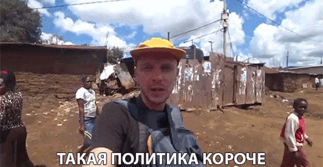 a man wearing a yellow hat and a backpack is walking down a dirt road in a foreign language