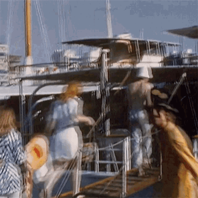 a group of people are walking down stairs to a boat with a woman holding a hat