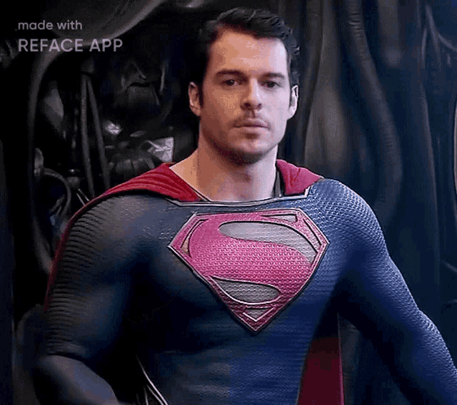 a man in a superman costume is standing in front of a black curtain and looking at the camera .