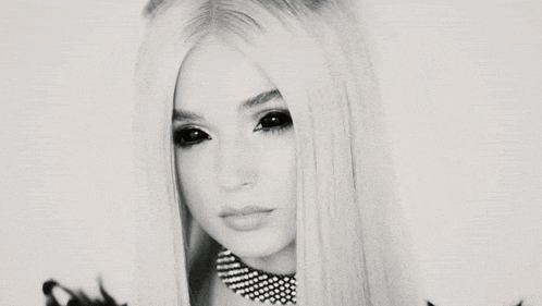 a black and white photo of a woman with long blonde hair wearing a choker necklace .