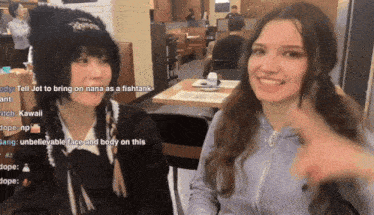 two girls are sitting at a table in a diner and one of them is wearing a black hat