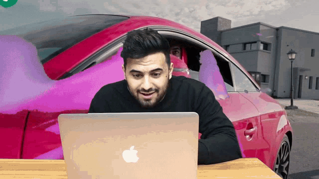 a man sitting in front of an apple laptop computer