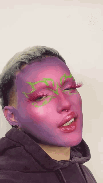 a person with purple and pink makeup on their face is smiling