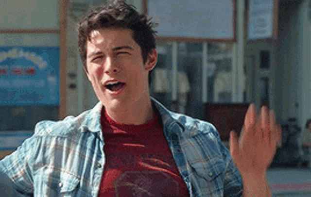 a man wearing a plaid shirt and a red shirt is waving his hand