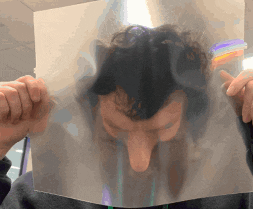 a man holds a piece of paper over his face