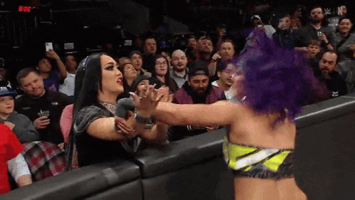 two female wrestlers are fighting in front of a crowd .