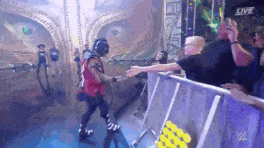 a wrestler is shaking hands with a fan while walking through a crowd .