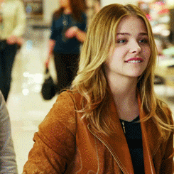 a woman wearing a brown jacket is smiling in a store