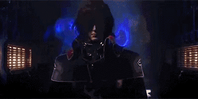 a man in a military uniform is standing in a dark room with blue lights behind him .