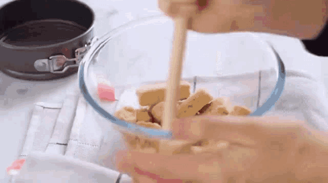 a person is using a wooden spoon to mix a bowl of food .
