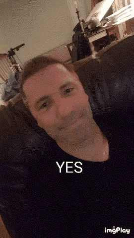 a man is sitting on a couch with the word yes written on his face