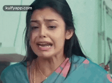 a woman in a blue saree is crying with her mouth open in a hospital room .