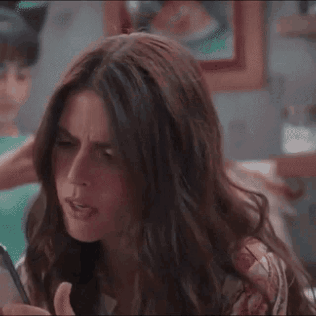 a woman with long hair is looking at her phone .