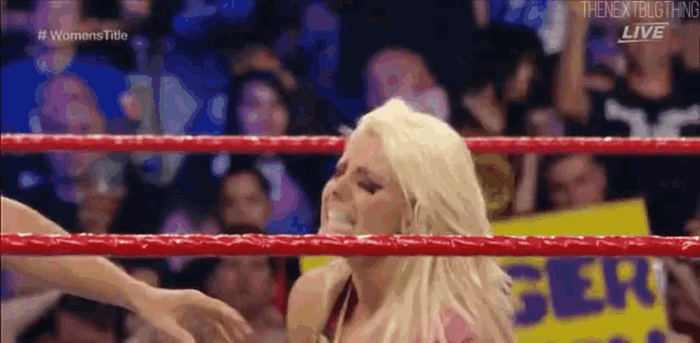 a woman is standing in a wrestling ring with a crowd behind her .