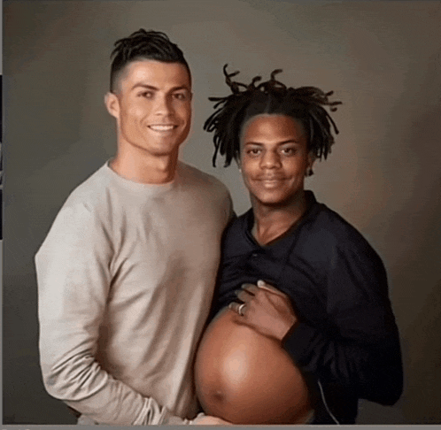 a man holding a pregnant woman 's belly while another man looks on