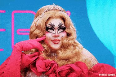 a drag queen is wearing a tiara and gloves and making a funny face