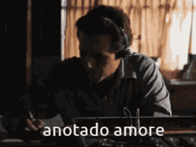 a man wearing headphones is typing on a typewriter with the words anotado amore written below him .