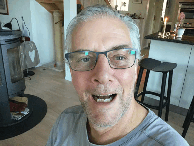 a man wearing glasses and a grey shirt is making a surprised face