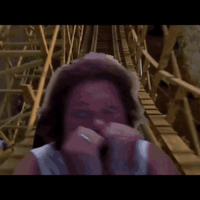 a woman is riding a roller coaster and covering her nose with her hands