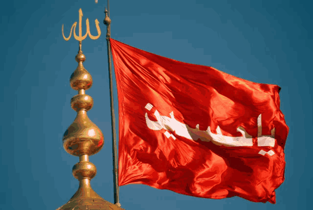 a red flag with arabic writing on it is hanging from a gold pole