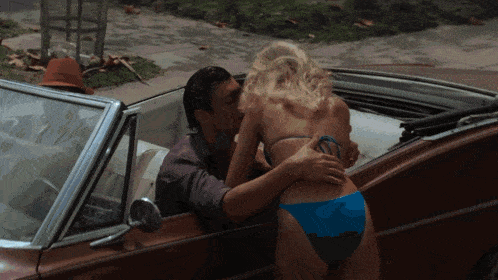 a man kisses a woman in a blue bikini