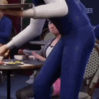 a cartoon character is standing next to a woman sitting at a table in a restaurant .