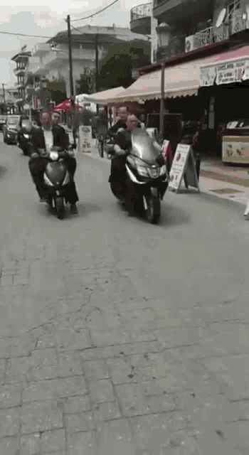 a group of men riding scooters down a street