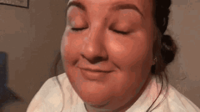 a woman is smiling with her eyes closed and her mouth open .