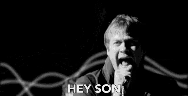 a man is singing into a microphone in a black and white photo with the words hey son written on the bottom .