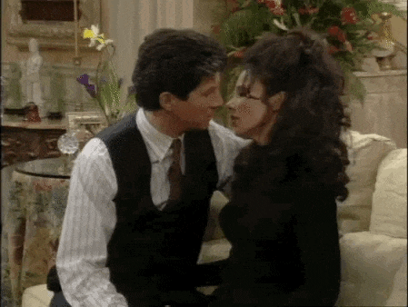 a man and a woman are kissing in a living room while sitting on a couch .