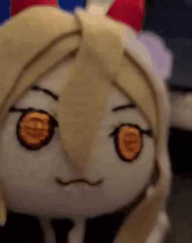 a stuffed animal with blonde hair and big orange eyes is making a face .