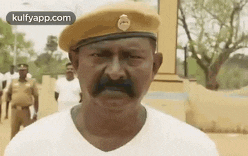 a man with a mustache wearing a hat and a white shirt .