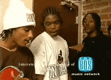 a group of young men are standing in front of a box music network advertisement