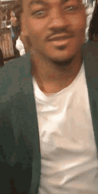 a man wearing a green jacket and a white shirt is smiling for the camera .