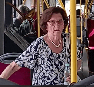 an older woman wearing glasses and a pearl necklace is standing on a bus .