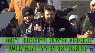 a man in a philadelphia eagles sweatshirt stands in front of a microphone
