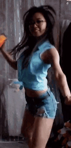 a woman in a blue shirt and shorts is dancing and holding a bag of doritos