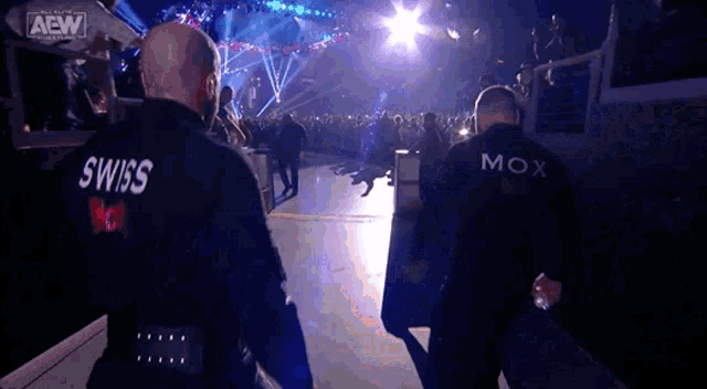 two men wearing black jackets with swiss and mox on them