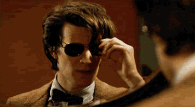 a man wearing sunglasses and a bow tie looks at himself in a mirror