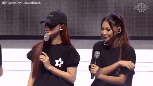 two women standing next to each other with binverse day 1 soundcheck in the corner