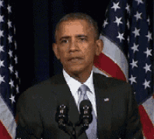 barack obama is giving a speech in front of a microphone in front of an american flag