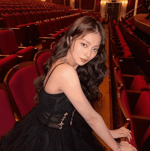 a woman in a black dress sits in a theater