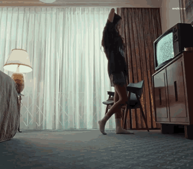 a woman is dancing in front of a television with the word archive on the bottom right