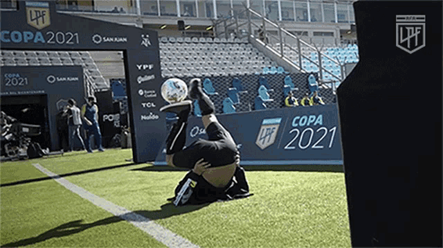 a man is kneeling on a soccer field holding a soccer ball in front of a sign for copa 2021