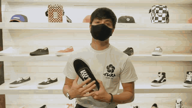 a man wearing a mask holds a shoe in front of a display of shoes