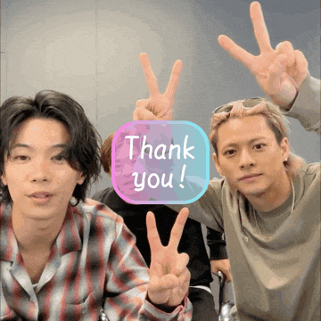 two men giving the peace sign with a thank you sign in the background
