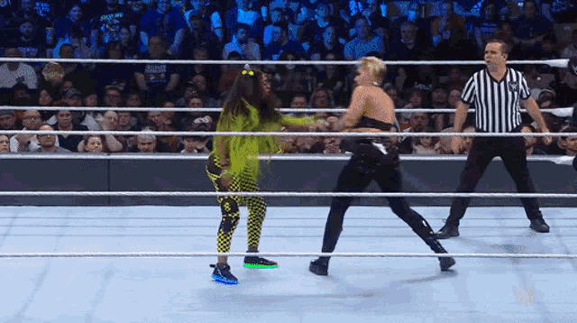 two women are wrestling in a ring with a referee