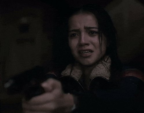 a woman is crying while holding a gun in her hand in a dark room .