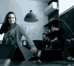 a woman in a grey shirt is dancing in a room with other people .